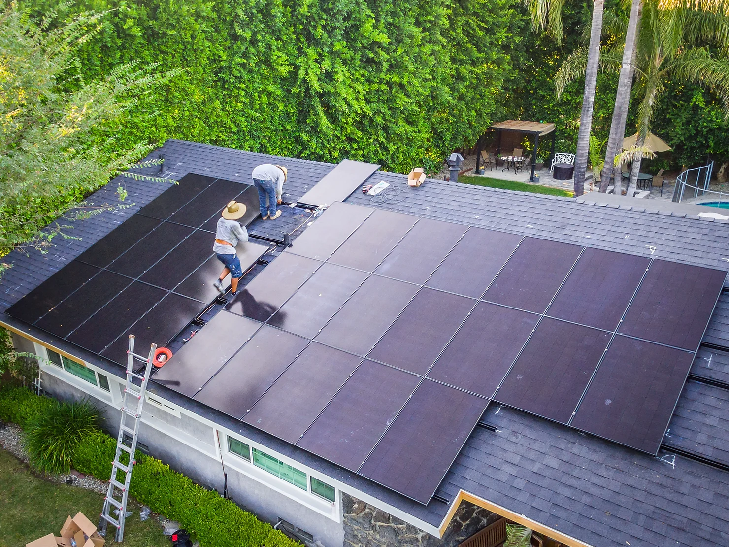 workers on top of roof installing solar panels on residential home