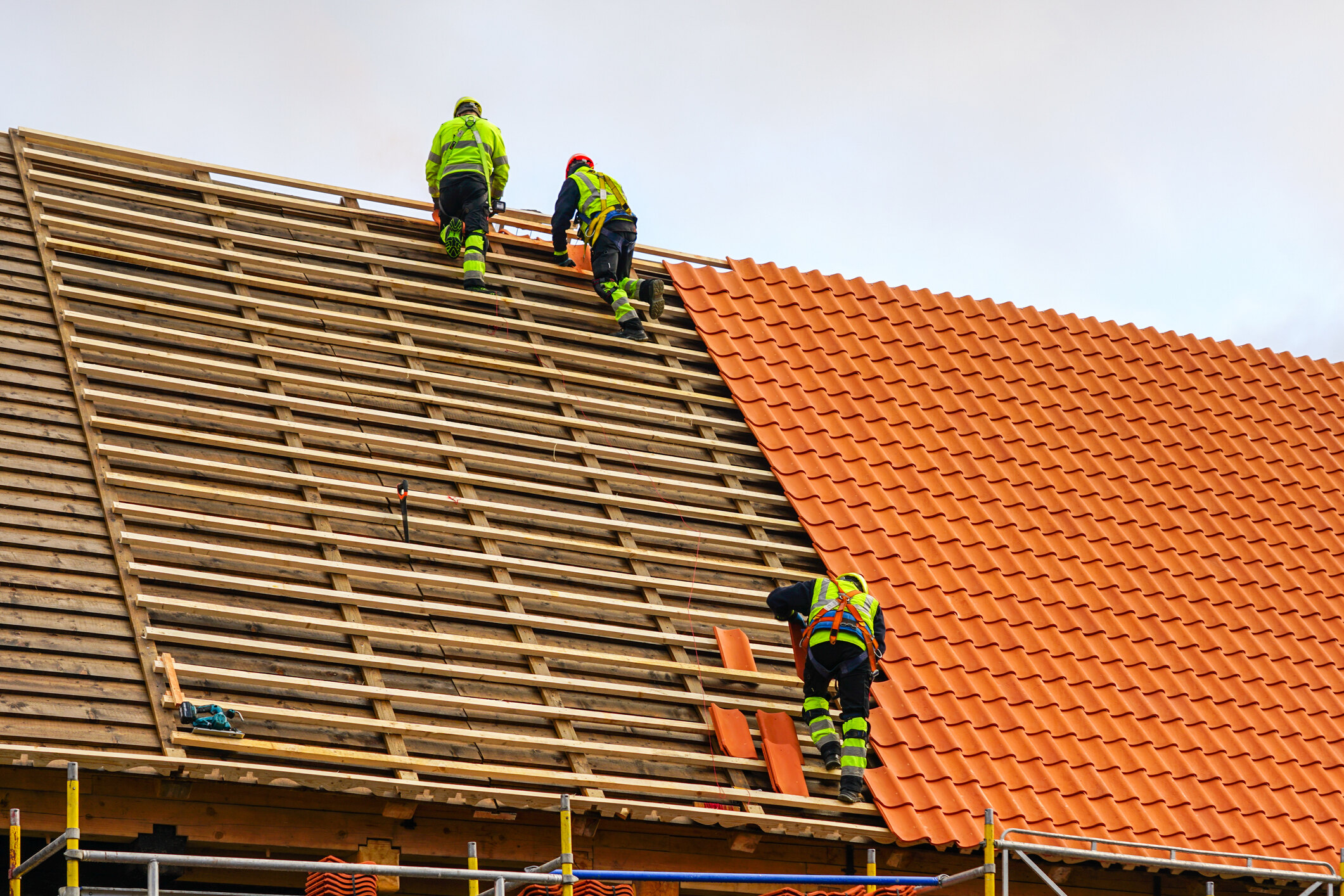 three-roofers-in-protective-workwear-installing-clay-tiles