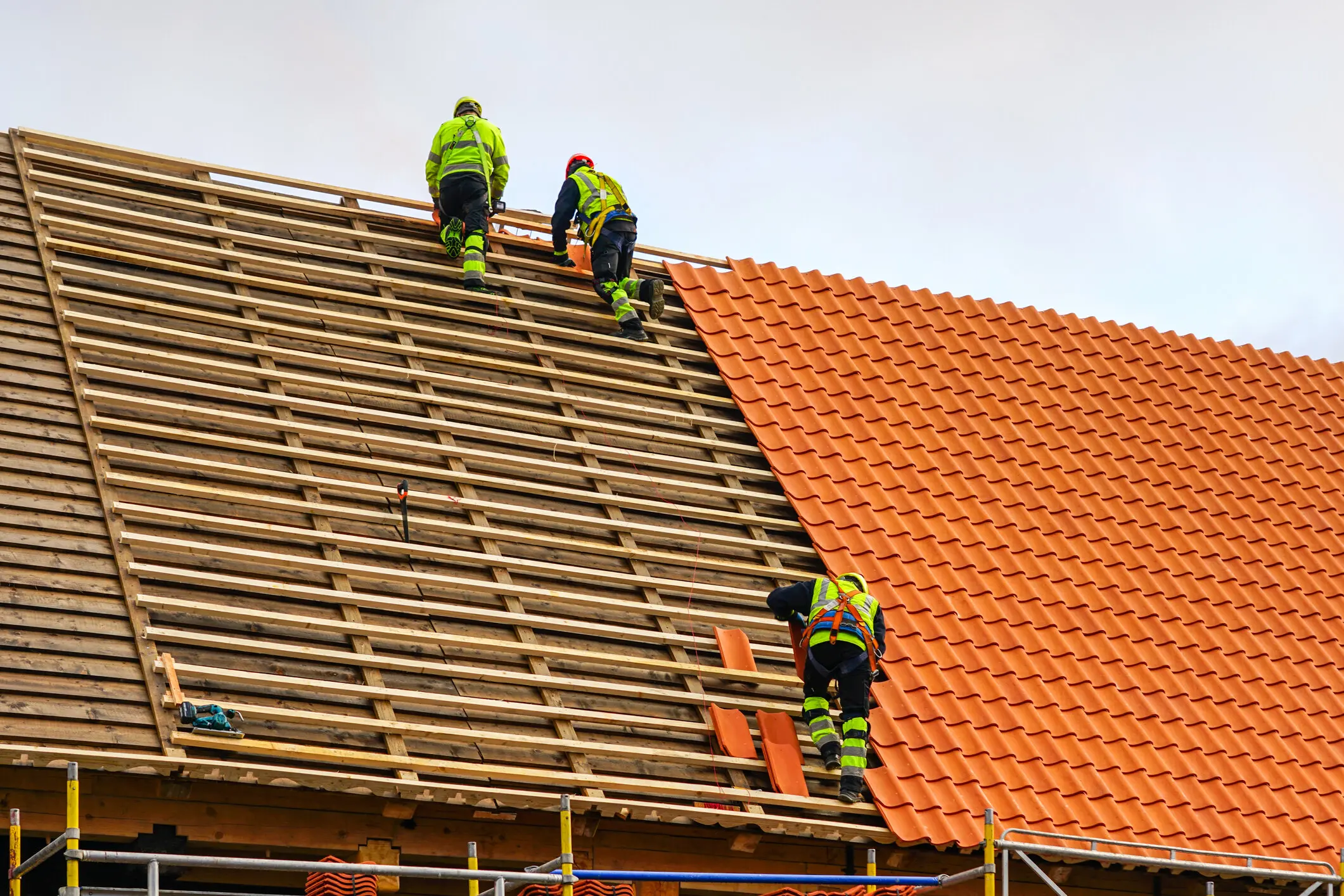 three-roofers-in-protective-workwear-installing-clay-tiles
