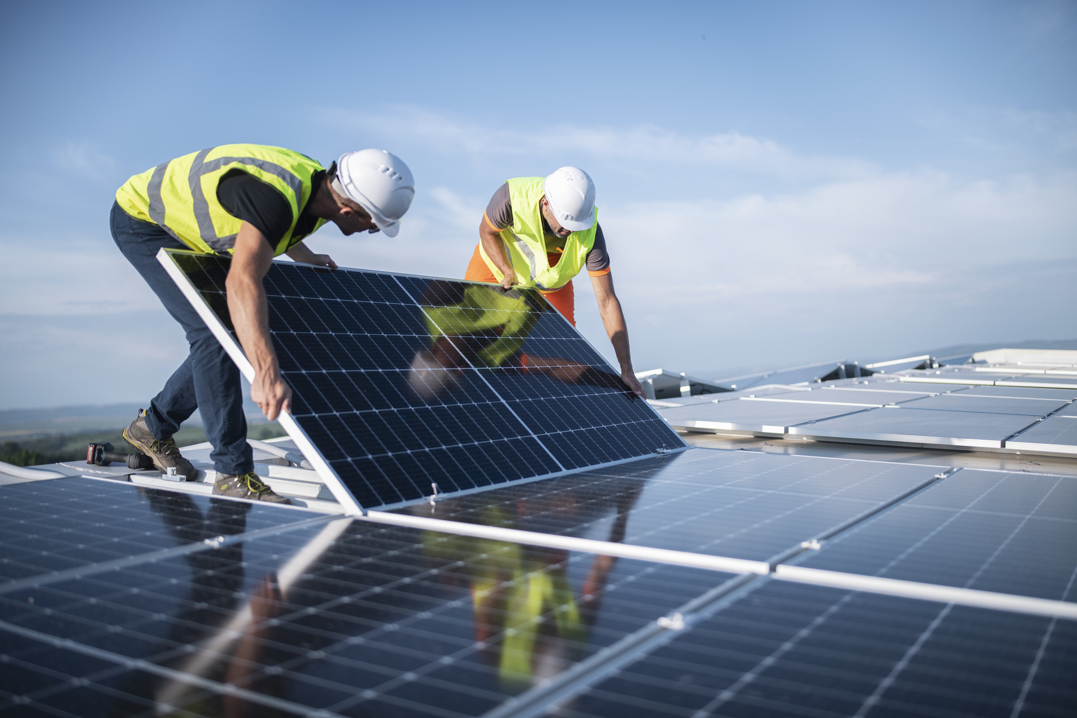 two-engineers-installing-solar-panels-on-roof